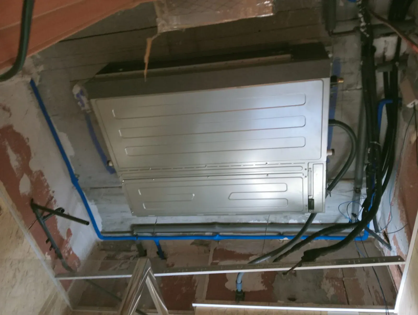 Unidad interior de aire acondicionado por conductos colgada del techo antes de cerrar el falso techo