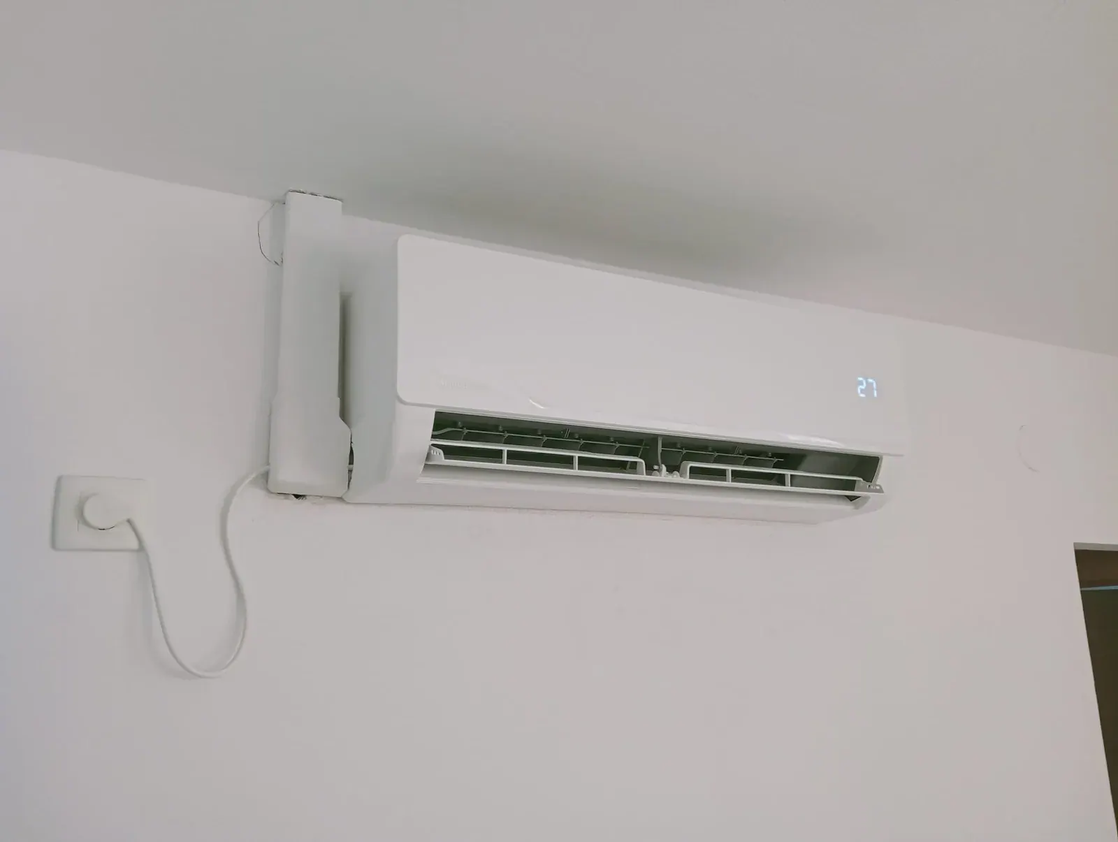 Split de aire acondicionado de pared instalado y en marcha, con la canaleta rematada hasta la toma de corriente