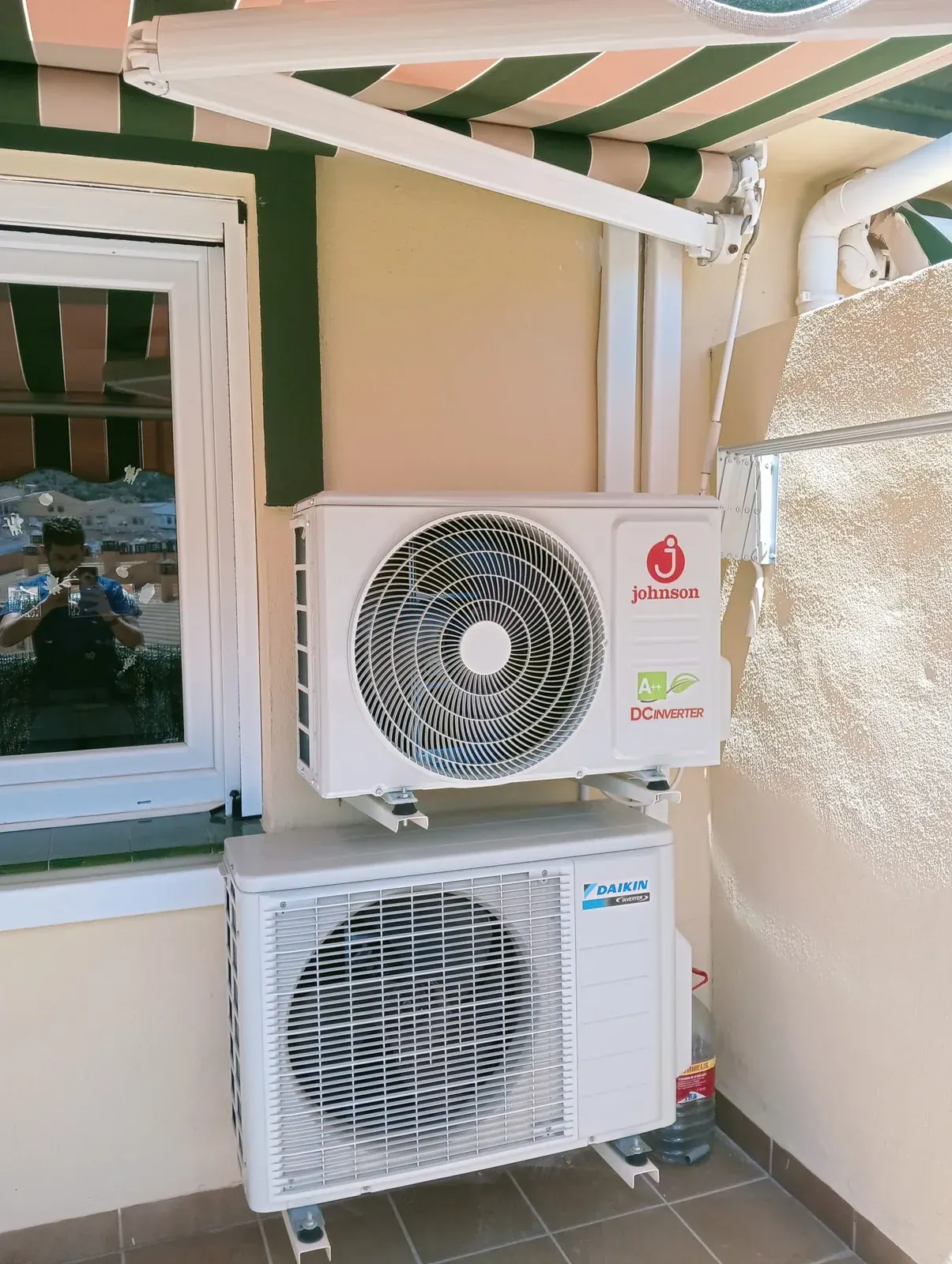 Dos unidades exteriores de aire acondicionado instaladas en la terraza de una vivienda, una sobre soportes de pared y otra apoyada en el suelo